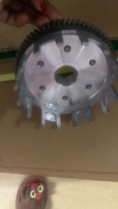 Motorcycle wheel with sprocket and tools on dirt ground in DIY repair setup.