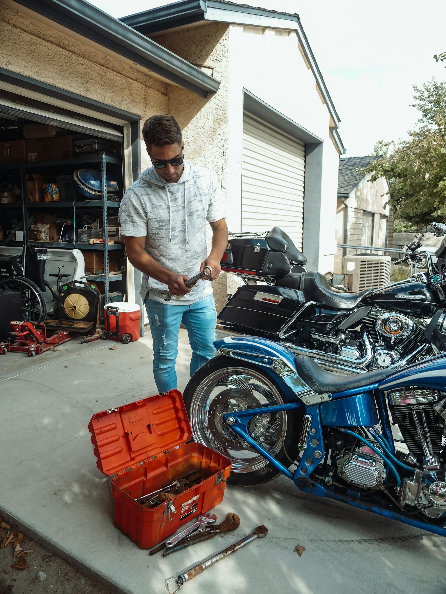 A man working on a motorcycle in a garage, surrounded by tools and engine parts.
