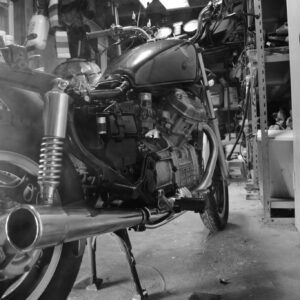 Classic motorcycle captured in monochrome inside a cluttered workshop.