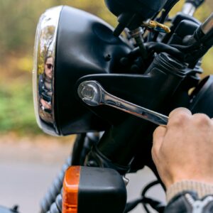 Hand tightening bolts on a motorcycle, highlighting detailed mechanical maintenance.