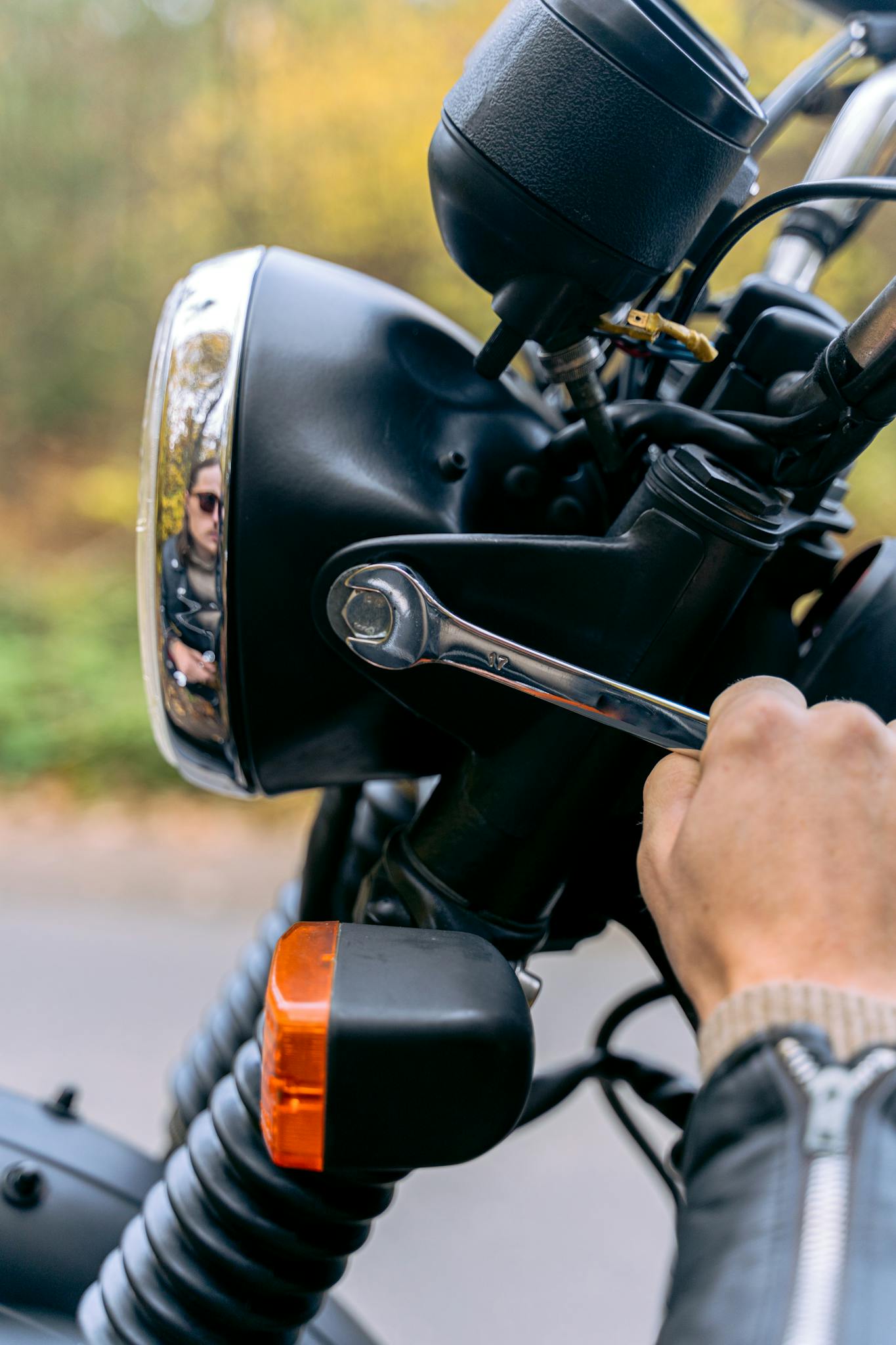 Hand tightening bolts on a motorcycle, highlighting detailed mechanical maintenance.
