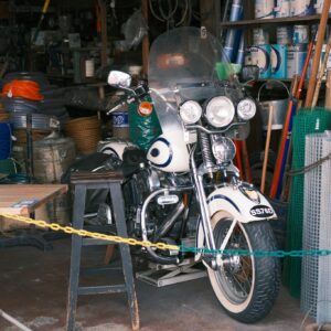 Vintage motorcycle with tools and supplies in a cluttered workshop, showcasing a retro vibe.